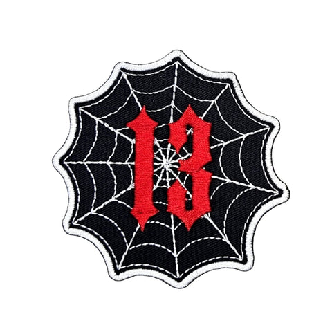 black embroidered patch in the shape of a spiderweb with the number 13 in red Old English font in front