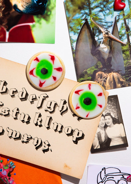 2 1/2" round magnet set of two magnets in the shape of sugar cookies with green, red, black and white eyeball frosting decoration. Shown on fridge