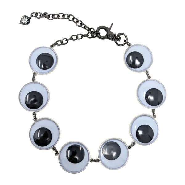 Choker style necklace with 8 linked large plastic black and white googly eyes with gunmetal finish metal link chain extender and matching swivel hook clasp closure. Shown flat