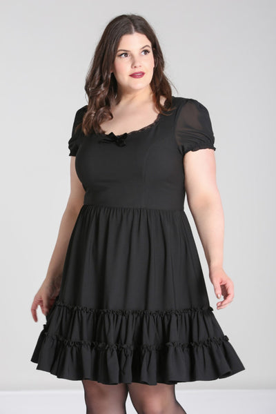 black mini dress featuring princess seamed fitted bodice with a lace edged angled v-neckline and velvet bow detail at the bust, sheer puffed short sleeves with elasticized cuffs, and a gathered full above the knee length skirt finished with a double row of flounces. shown on model.