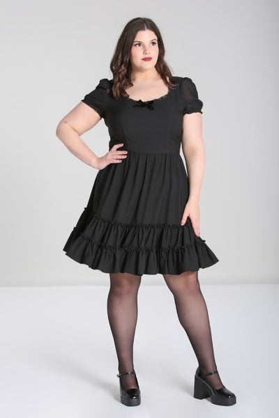 black mini dress featuring princess seamed fitted bodice with a lace edged angled v-neckline and velvet bow detail at the bust, sheer puffed short sleeves with elasticized cuffs, and a gathered full above the knee length skirt finished with a double row of flounces. shown on model.