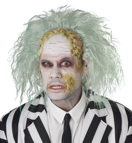 A person wearing a Beetlejuice-style costume wig with messy pale green hair, yellow-and-white face makeup, and a black-and-white striped blazer over a white shirt and black tie, photographed against a plain white background. Shown from front