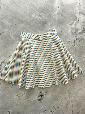 A cotton skater style mini skirt with a wide waistband and a diagonal rainbow stripe pattern on a white background. Shown flat