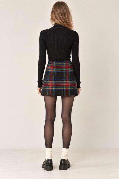 model wearing a black a-line mini skirt in a Black Stewart tartan pattern with red, green, blue, and yellow on a black background. Shown from back