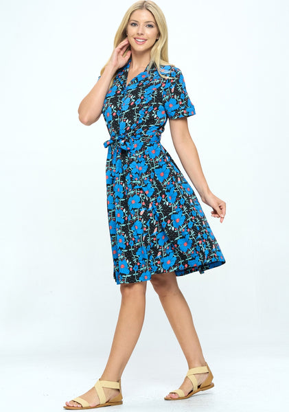 Model wearing black background blue and pink floral vertical vine print shirtwaist dress with notched v-collar, short sleeves, self sash, pockets, and a just above the knee flared skirt. Shown from side