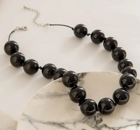 Black beaded necklace on a marble surface