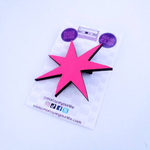 asymmetrical starburst hair clip made of UV reactive neon pink acrylic shown on backing card