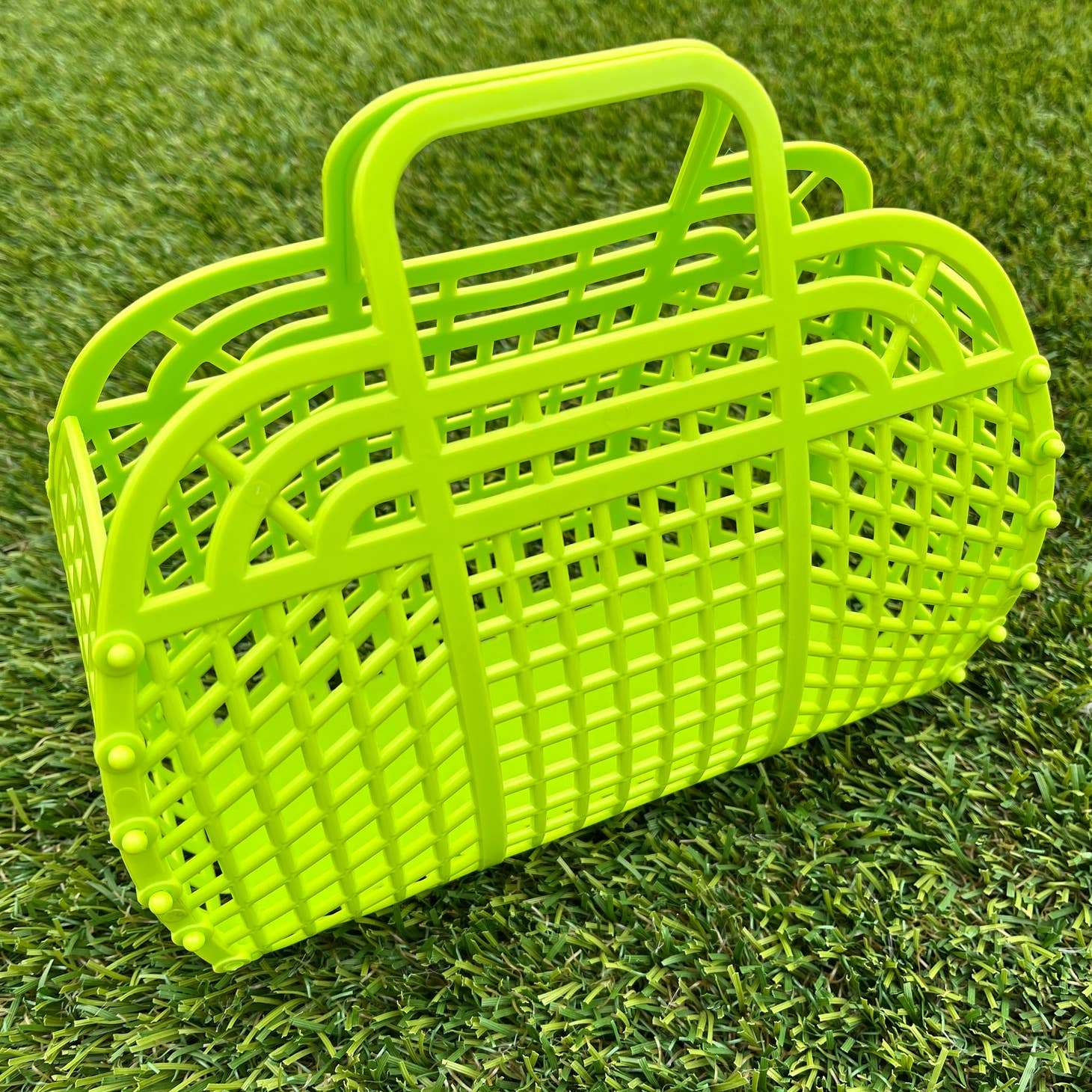 A small lime green rectangular handbag made of plastic with a lattice pattern