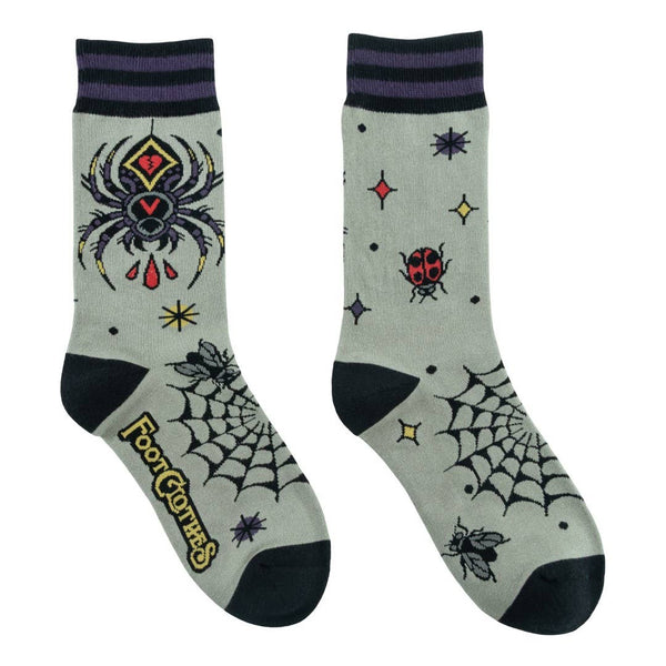 socks with tattoo flash-style spider, ladybug, fly, and web designs on a light sage green background with black and purple striped cuffs and black toes & heels. Shown flat