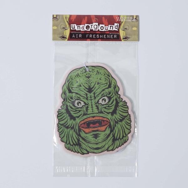 Green creature from the black lagoon face air freshener with a hanging cord shown in packaging on a white background