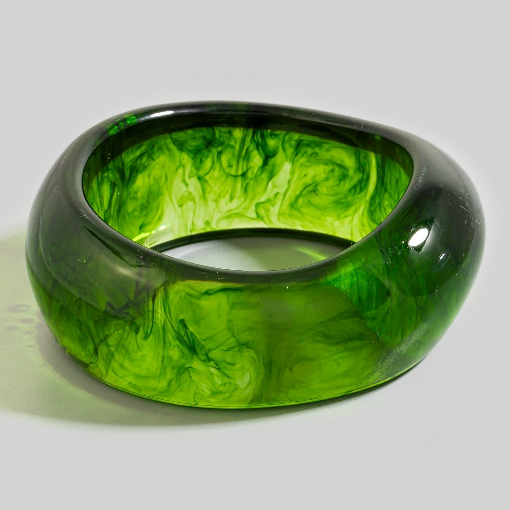 translucent bright green bangle with rounded asymmetrical shape and dark green swirled marbling