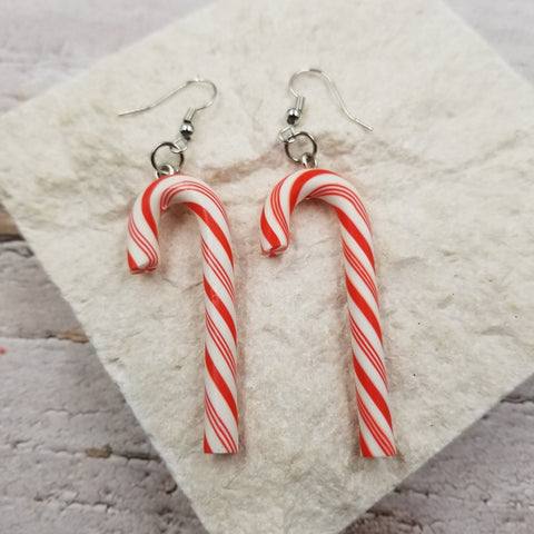 a pair of dangle earrings in the shape of red and white striped candy canes