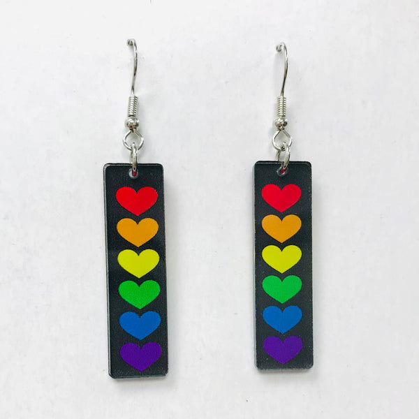 Pair of dangle earrings with acrylic rainbow heart charms on a white background
