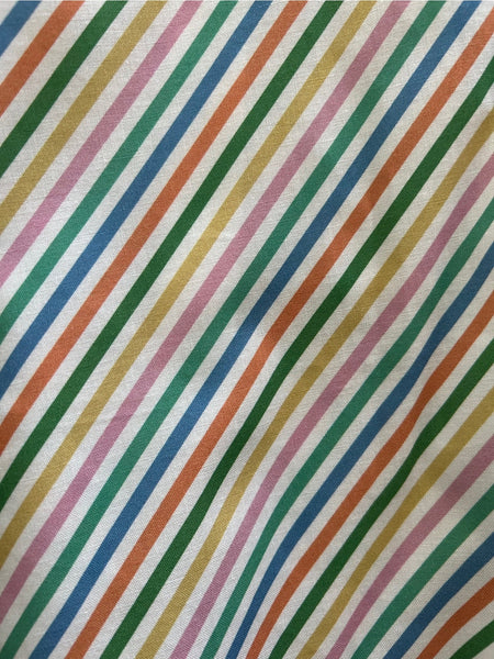 A cotton skater style mini skirt with a wide waistband and a diagonal rainbow stripe pattern on a white background. Shown flat in close up