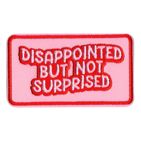 pink embroidered patch with red border and "DISAPPOINTED BUT NOT SURPRISED" written in pink bubble letters with red outline