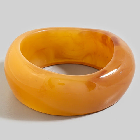 butterscotch yellow-orange bangle with rounded asymmetrical shape and dark orange swirled marbling