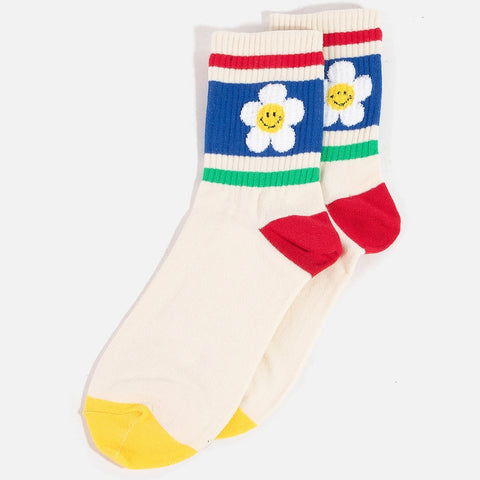 Creamy off-white crew socks with knit in horizontal striped pattern in red, blue, and green with red heels and yellow toes. On side of ankles there is a knit in fuzzy design of a white daisy with yellow happy face in the middle