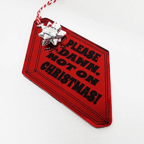 Laser cut red mirrored acrylic ornament in the shape of a gift box with metallic gift bow and the quote “Please Dawn, not on Christmas!”