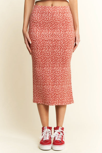model wearing a pink background red leopard print knit high waisted midi skirt with elastic waistband and side slit. Shown from front in close up