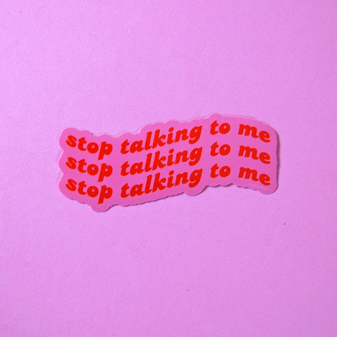 Die-cut sticker with red swirled lettering on a pink background “stop talking to me”