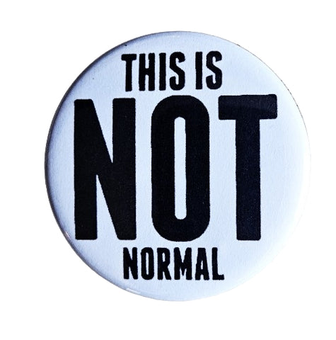 1.25 round pinback button with white background and message in black lettering “THIS IS NOT NORMAL” —“NOT” is written in font taking up most of the button
