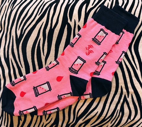 Pink socks with black guillotines and red drops of blood and black toes, cuffs, and heels on a zebra-patterned surface