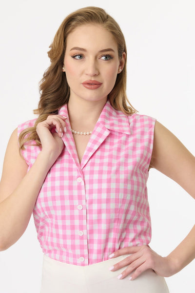 Model wearing sleeveless cotton button-up blouse in white and pink gingham pattern with pointed notched collar. Shown tucked into pants from front