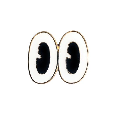 gold metal enamel pin of a large pair of oval-shaped cartoon eyes with black irises and bright white whites. Shown flat