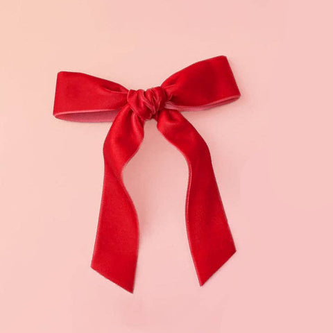 bright red velvet hair bow on a light pink background