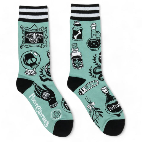 unisex mint blue-green crew socks with black and white striped cuffs & black toes/heels and all over pattern of potions, snakes, herbs, skulls, crystal balls, and moths in black and white. Shown flat