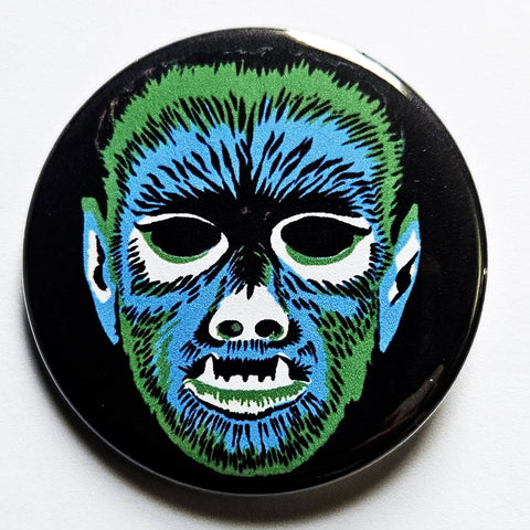 1.25 round pinback button with a stylized wolfman mask design in blue, green, and white on a black background