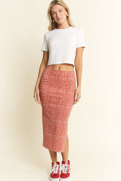 model wearing a pink background red leopard print knit high waisted midi skirt with elastic waistband and side slit. Shown from front