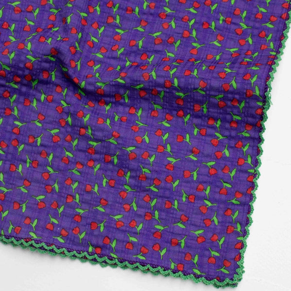 cotton seersucker square scarf in purple background ditsy red and green rosebud print with bright green scalloped embroidered trim. Shown folded in close up