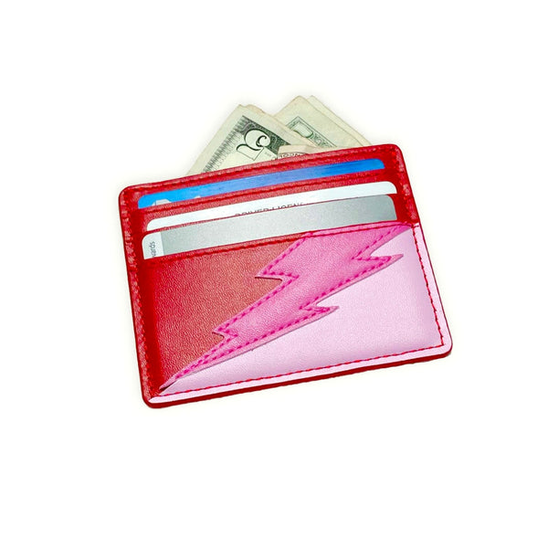 rectangular faux leather 6 slot card holder in bright red and bubblegum pink with diagonal hot pink faux leather lightning bolt applique in middle. Shown from front with cards and cash