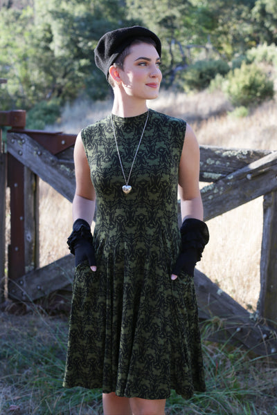 green and black patterned sleeveless mock turtleneck dress worn by a model in an outdoor setting