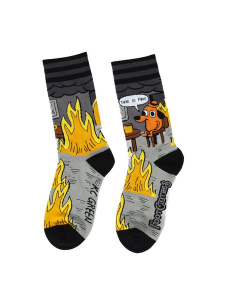 black, grey, yellow, and orange unisex crew socks with black and grey stripe cuffs and black toes/heels with all over pattern of a cartoon dog wearing a hat sitting at a kitchen table surrounded by flames with a speech bubble saying "THIS IS FINE." Shown flat