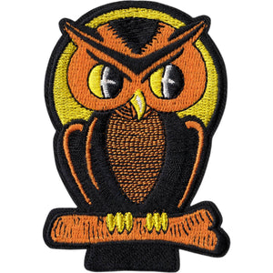 Embroidered patch of an owl with black body and orange head perched on a branch in front of a yellow full moon