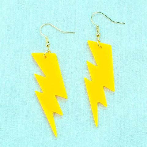 Yellow laser-cut acrylic lightning bolt dangle earrings on a blue background
