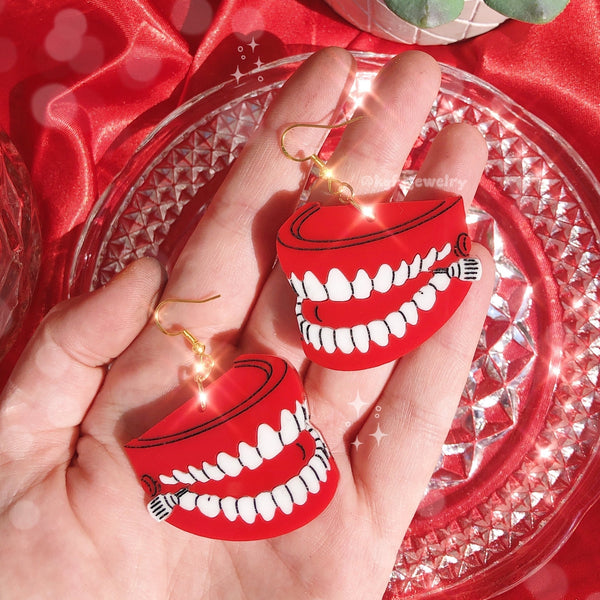 pair of laser-cut layered acrylic dangle earrings in the shape of wind-up chattering teeth with black detail