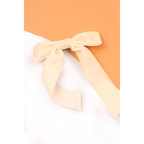 cream colored ribbon bow on a white surface with an orange background