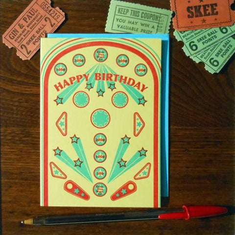 Rectangular letterpress birthday card meant to resemble playfield of a pinball machine. “Happy birthday” is written across the card with “Extra wish when lit” in one of the targets 