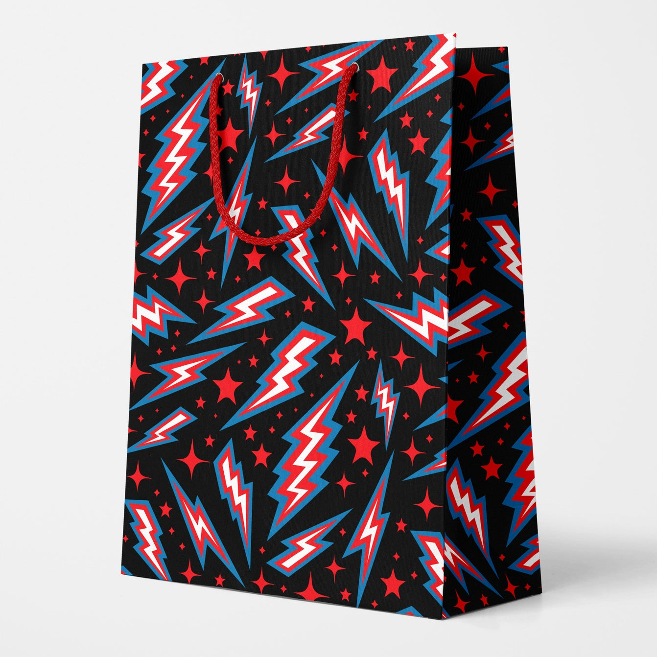 Rectangular gift bag in an all-over red, blue & white lightning bolt and red star pattern on a black background. Bag has red polyester rope handle