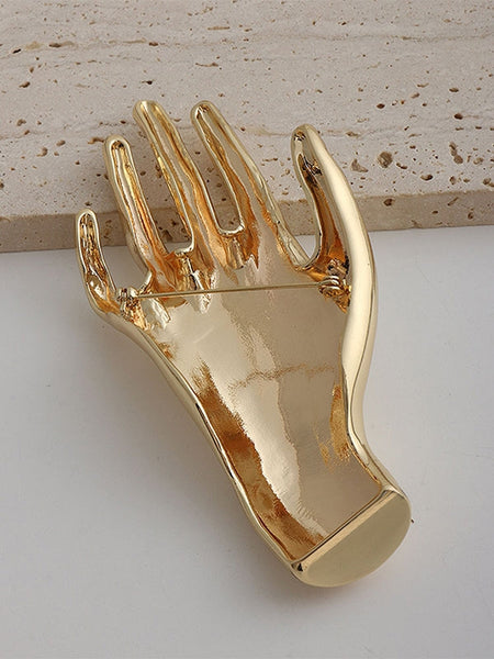 Gold metal brooch of an outstretched hand. Shown flat from the back