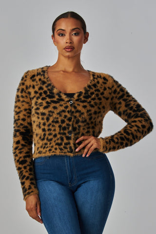 Woman wearing a leopard print sweater in a faux mohair material with long sleeves, slight v-neckline, and matte black plastic buttons. Shown from front