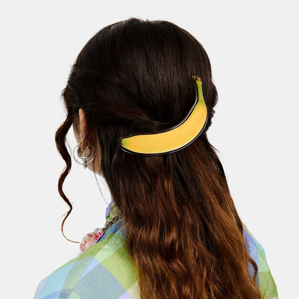 large acetate pinch clip style acetate barrette in a photorealistic yellow ripe banana design. Shown worn in model's hair