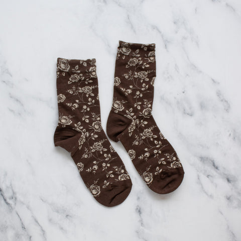 dark brown cotton socks with light knit-in pattern of roses, rosebuds, and their stems. Shown flat