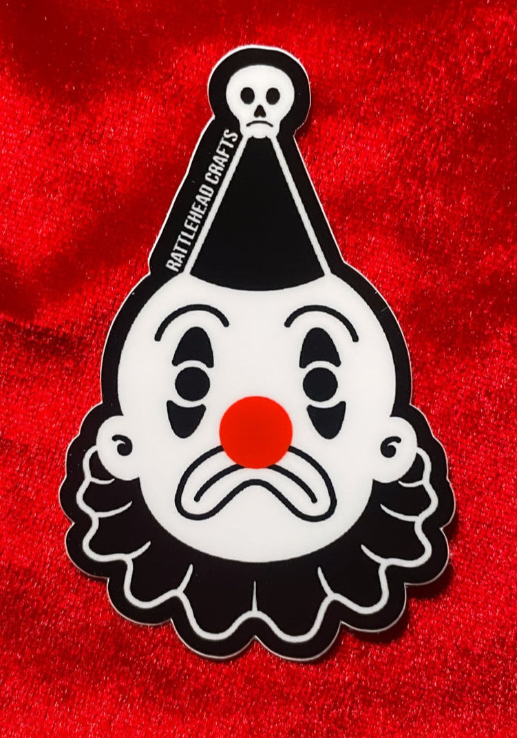 black and white frowning clown die-cut vinyl sticker shown on red velvet background