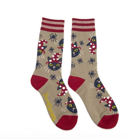 Unisex crew socks in light brown with red striped cuffs and red toes & heels. All over pattern of black cats wearing red and white dotted witch hats and small black spiders. Shown flat
