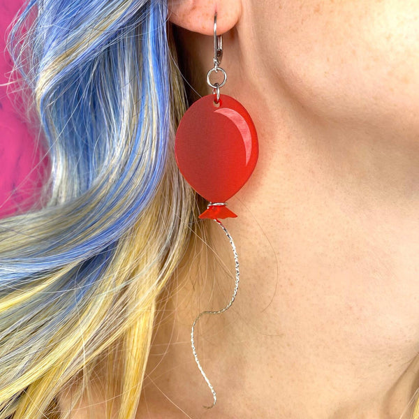 red frosted finish laser cut acrylic balloon dangle earrings with wavy sterling silver "string" wrapped around the bottom of each. Shown in close up on model
