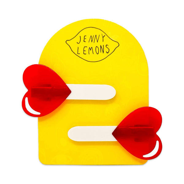 cellulose acetate hair clips in the shape of semi translucent red heart-shaped lollipops with sticks. Shown on backing card